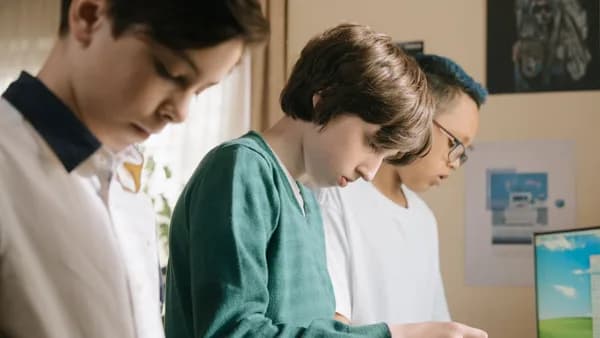 Three young students focused on a collaborative technology project in a classroom setting.