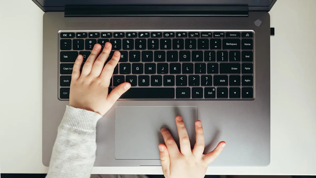 Child's hands typing on a laptop keyboard.