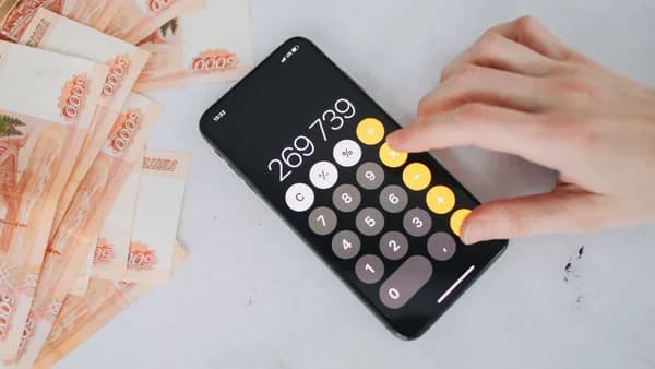 Person using smartphone calculator with Russian rubles on a table, representing financial planning.