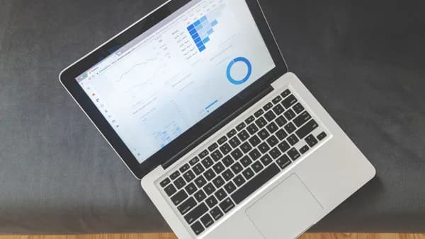 Overhead view of a laptop showing data visualizations and charts on its screen.