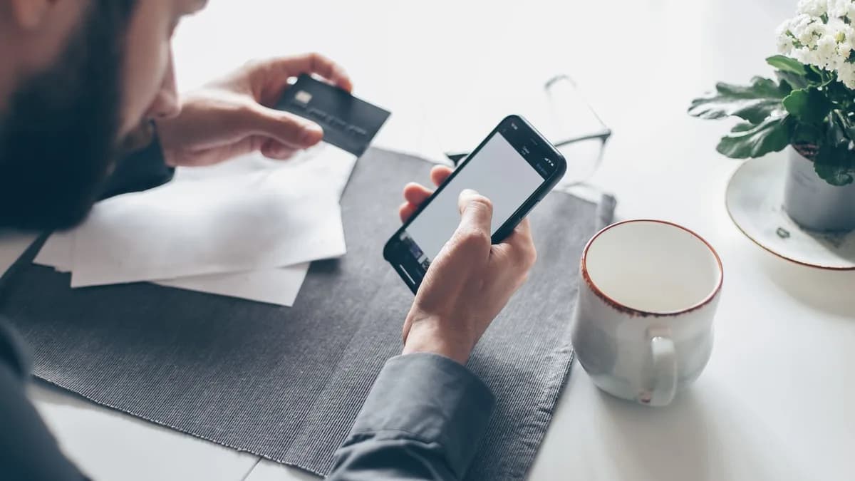 Man with a smartphone processing an online payment with a credit card. Soft light, modern lifestyle.