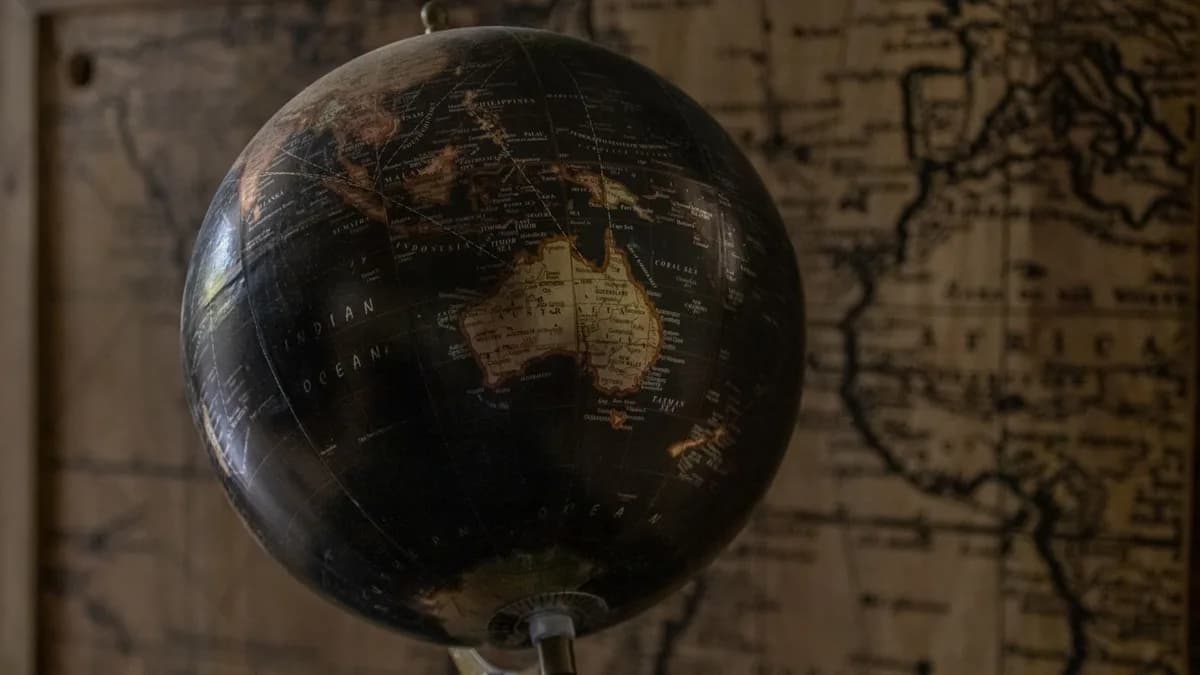 A vintage globe showcases Australia with a sepia world map in the background, offering a classic exploration theme.
