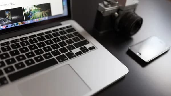 Lifestyle workspace setup with a laptop, camera, and smartphone on a desk.