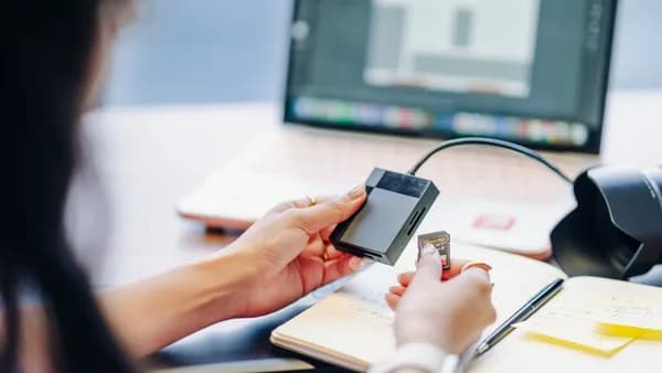 Close-up of a person using a card reader with a laptop, ideal for tech or remote work themes.