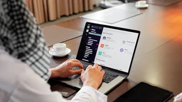 Businessman using messaging app on laptop in modern office, engaging in team collaboration.
