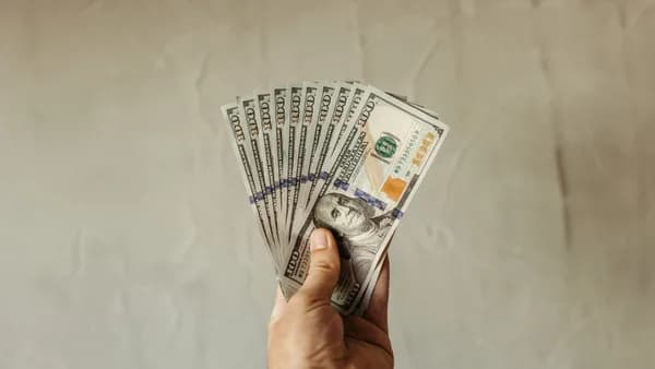 A close-up of a hand holding multiple US dollar bills, showcasing wealth and finance concepts.