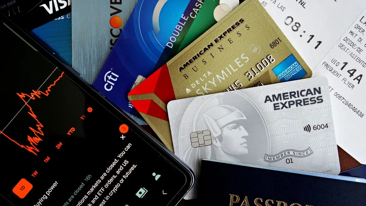 Flat lay of credit cards, passport, and a phone showing stock data, depicting finance and travel.