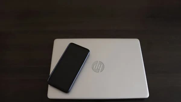 Close-up of a smartphone resting on an HP laptop, symbolizing modern technology integration.
