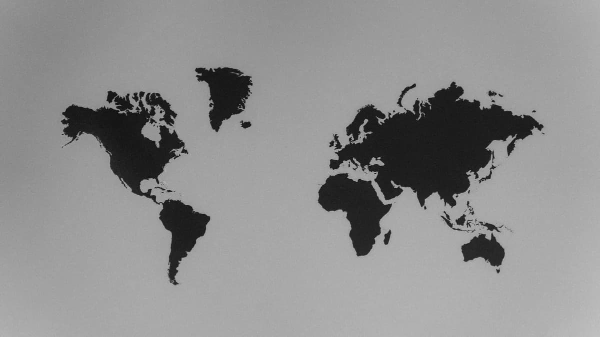 A simple black and white silhouette of a world map emphasizing continents against a stark background.
