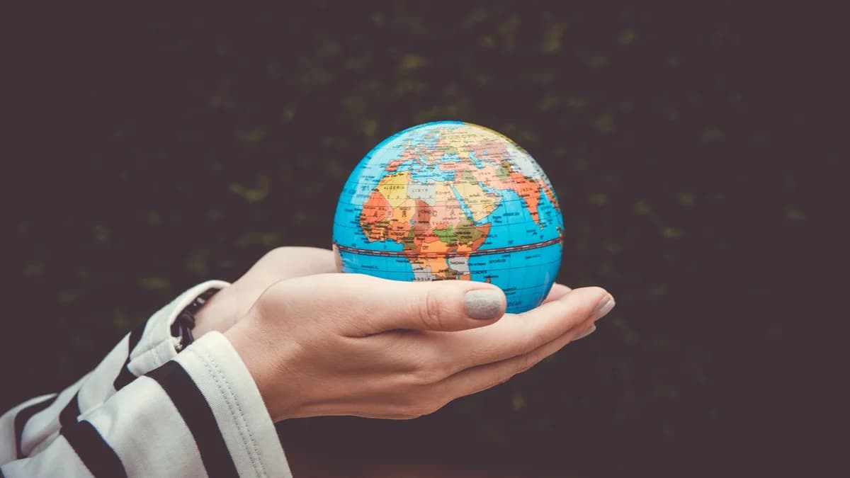 Person holding a small globe in hands, showcasing Earth. Ideal for global concepts or travel themes.