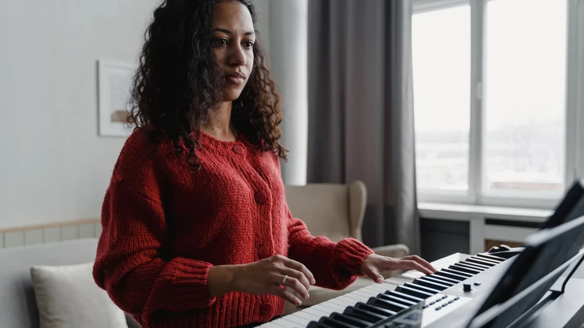 Woman in red sweater focused on playing the piano in a cozy home setting.