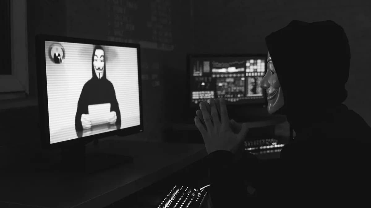 Monochrome image of a masked hacker on a video call, showcasing cyber security themes.