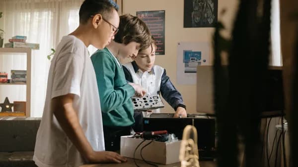 Three young teens work together on a computer project indoors, exploring hardware and technology.