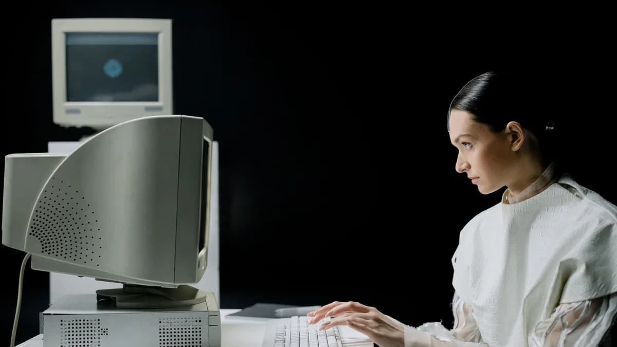 A woman typing on a retro CRT computer in a modern laboratory setting.