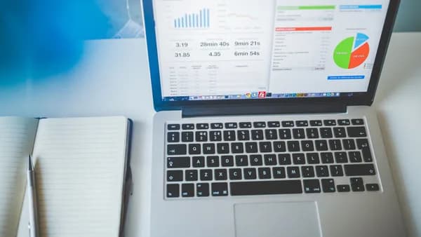 Laptop displaying charts and graphs next to a notebook, ideal for business and tech themes.