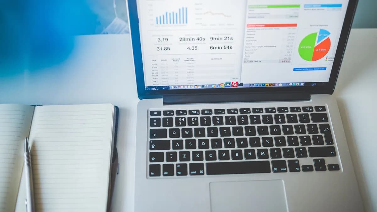 Laptop displaying charts and graphs next to a notebook, ideal for business and tech themes.