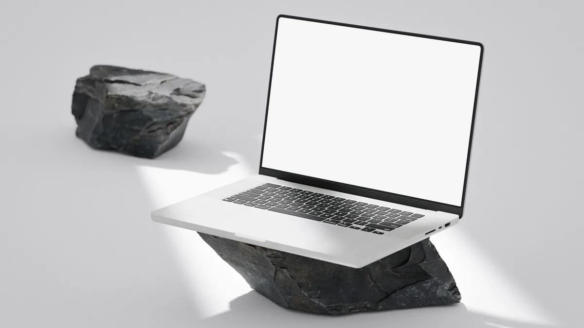 Elegant laptop with blank screen balanced on rocks in a minimalist setting.