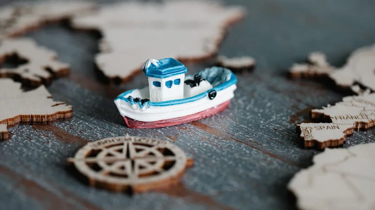 A close-up of a toy boat on a wooden map with a compass, representing travel and navigation.