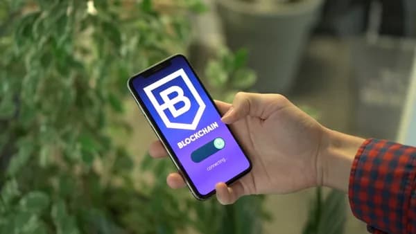 Close-up of a smartphone showing a blockchain app screen held by a hand.