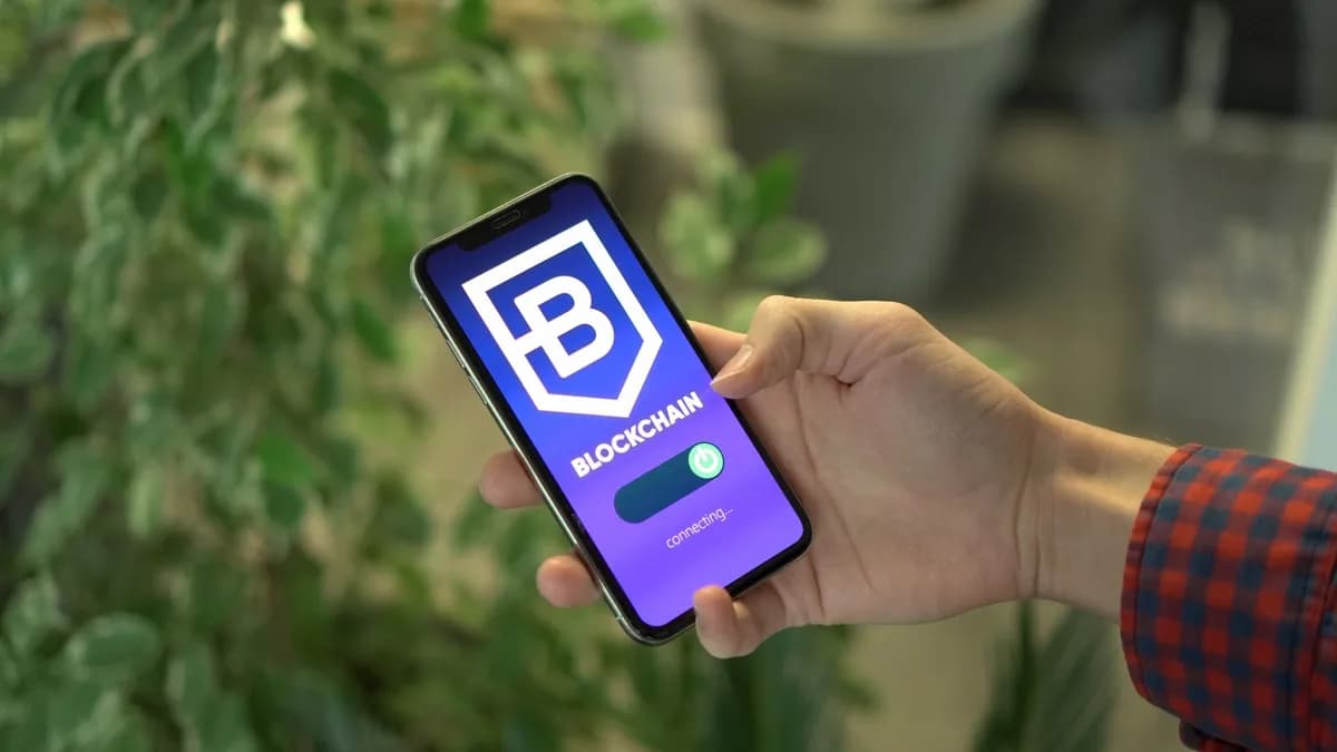 Close-up of a smartphone showing a blockchain app screen held by a hand.