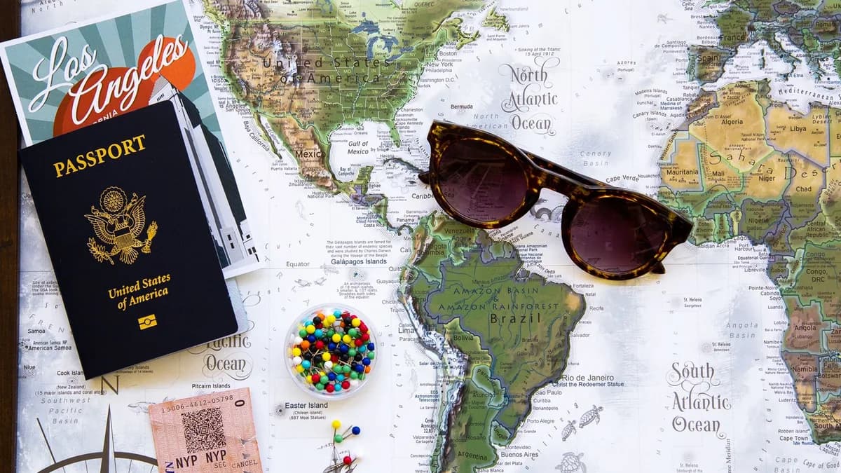 Flat lay of travel essentials with a world map, passport, and sunglasses.
