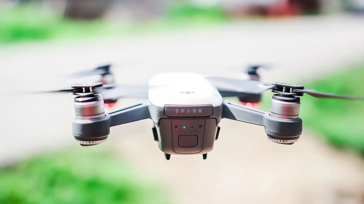 A front view of a DJI Spark drone flying in a blurred outdoor setting, capturing technology in motion.