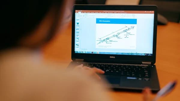Female engineer working on laptop reviewing technical engineering presentation.