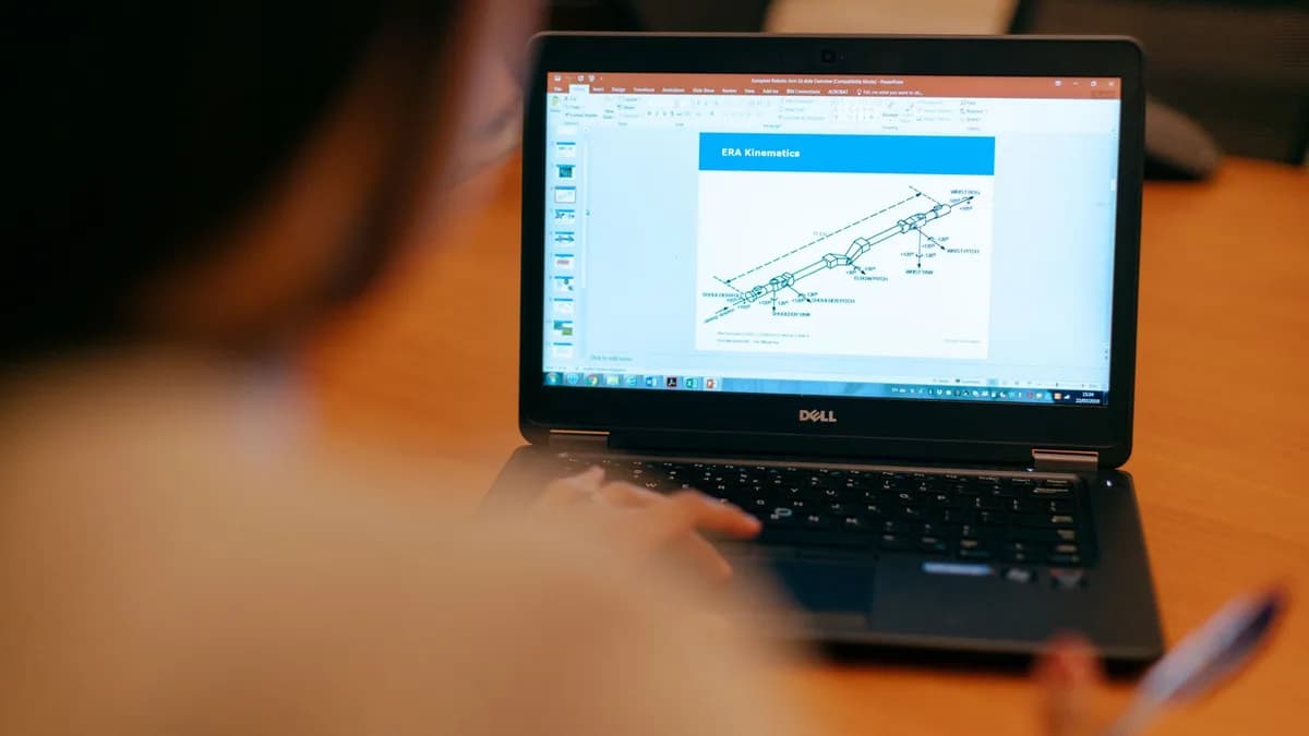 Female engineer working on laptop reviewing technical engineering presentation.