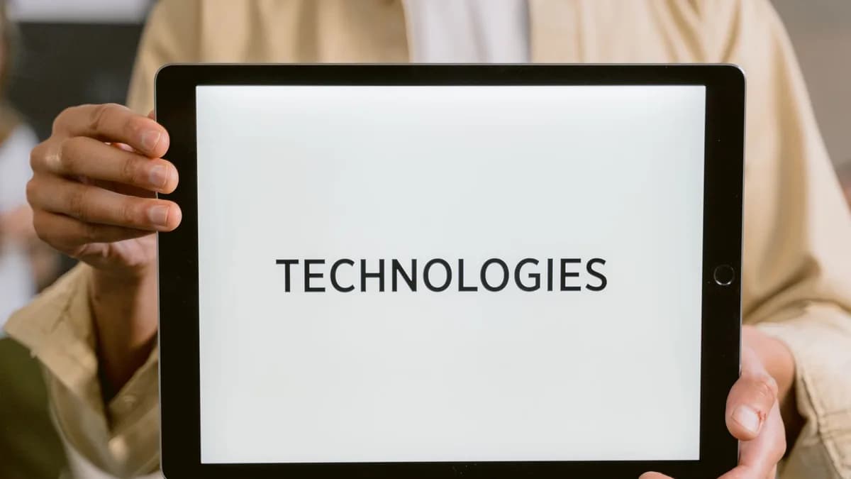 Close-up of a person holding a tablet with the word 'Technologies' on the screen.