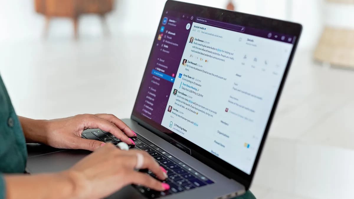 Woman typing on a laptop using a messaging app in a home setting, close-up of hands.