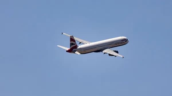 Wide shot of a commercial airplane flying high in a clear blue sky, showcasing modern aviation.