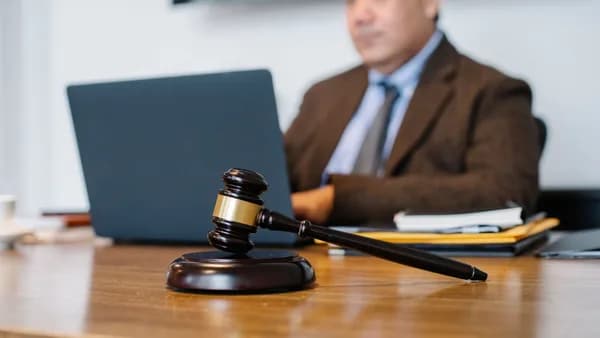 Crop concentrated Asian male judge in formal clothes sitting using modern netbook while working in law office