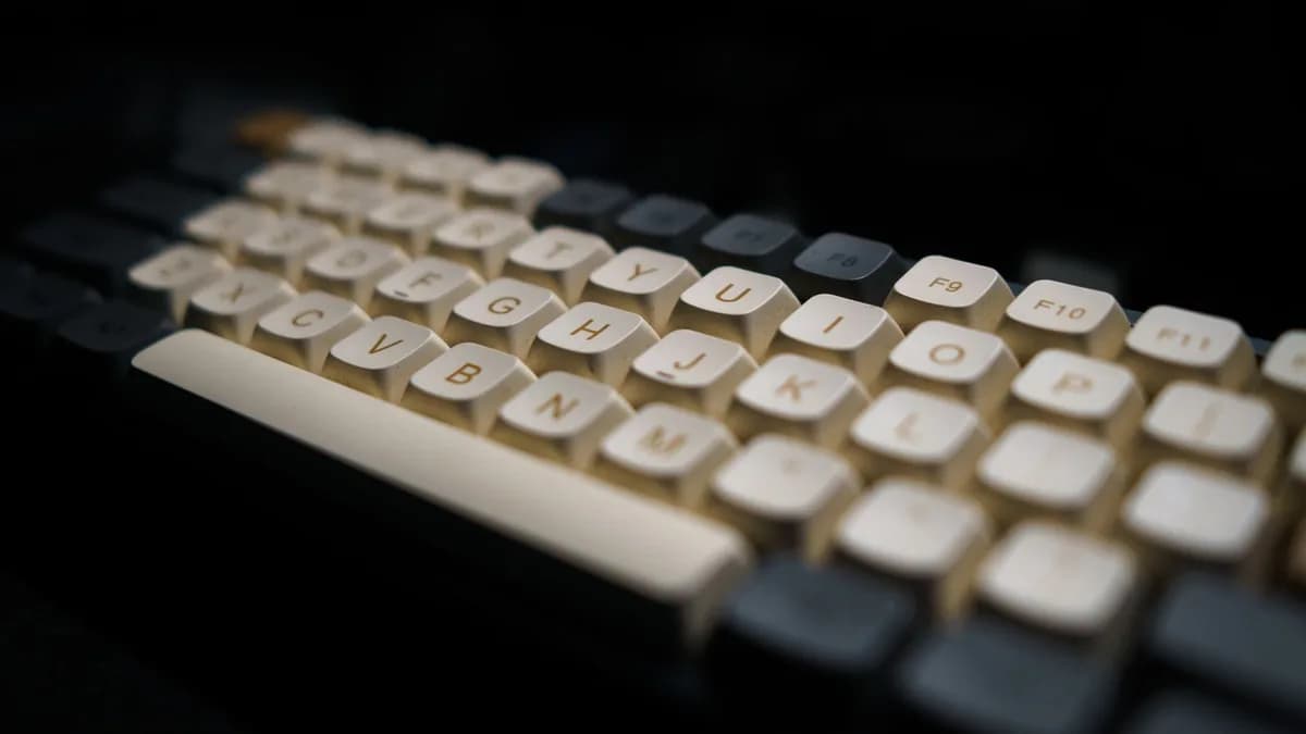 Close-up of a modern mechanical keyboard with white keycaps in a dark setting.