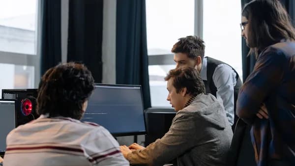 Group of developers working together on a computer programming project indoors.
