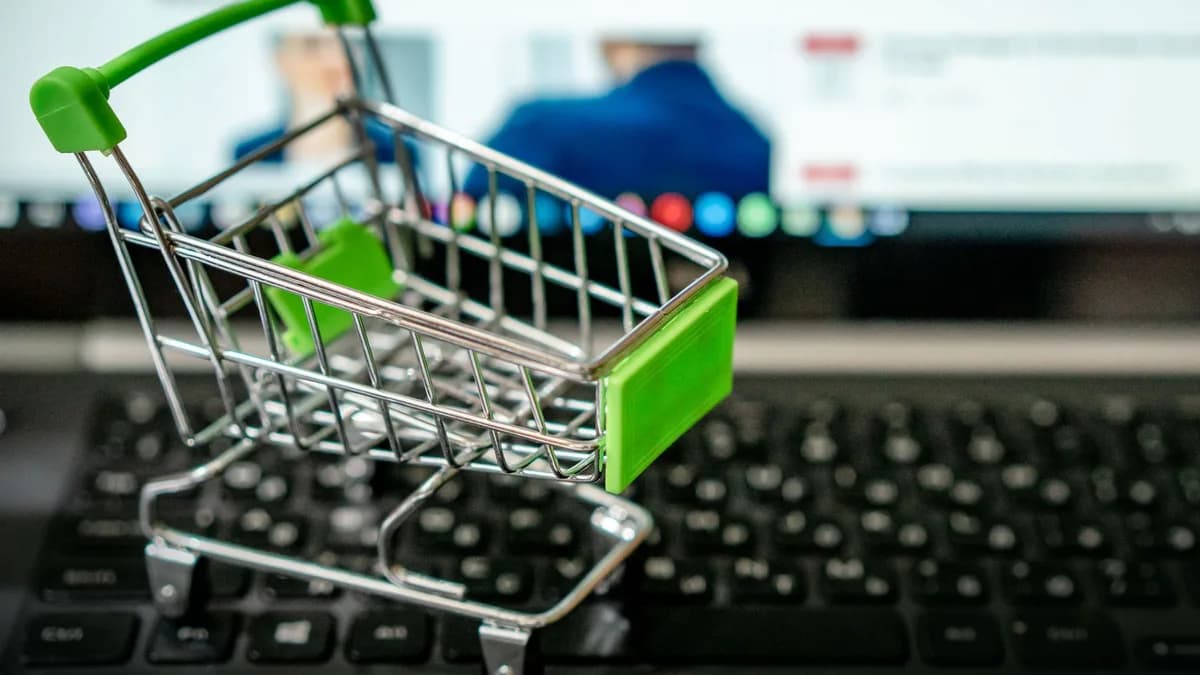 Miniature shopping cart placed on a laptop keyboard, symbolizing online shopping.