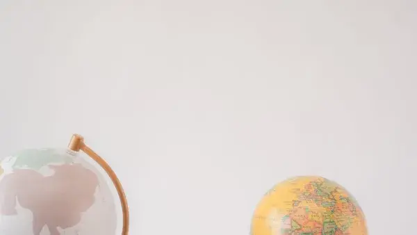 A minimalist image showcasing two globes against a light gray background offering ample copy space.