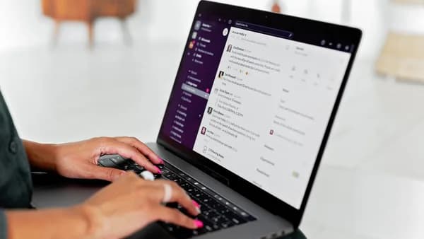 A woman types on a laptop using a messaging app in a modern office setting.