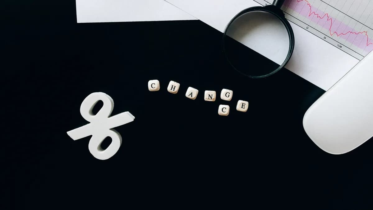 Magnifying glass on financial documents with a percentage sign, symbolizing economic change.