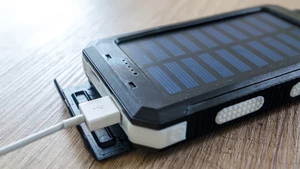 A close-up of a solar charger with a USB connection on a wooden surface, showcasing modern technology.