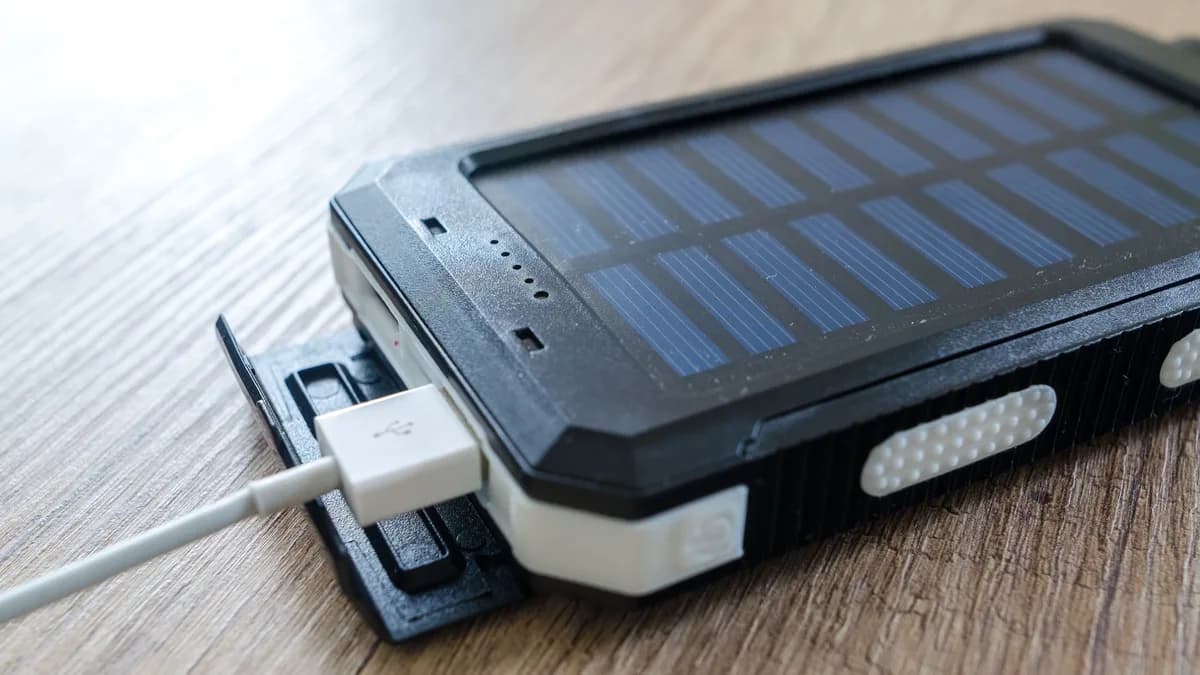 A close-up of a solar charger with a USB connection on a wooden surface, showcasing modern technology.