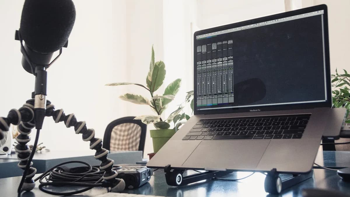 A detailed studio setup featuring a laptop and microphone on a desk for audio production.