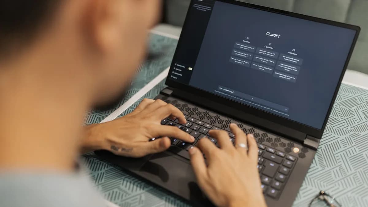 A focused individual types on a laptop running AI software indoors.