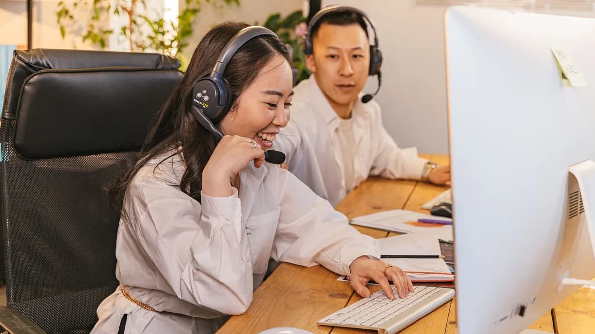 Two call center agents working together, focused and engaged at their desks, communicating via headsets.