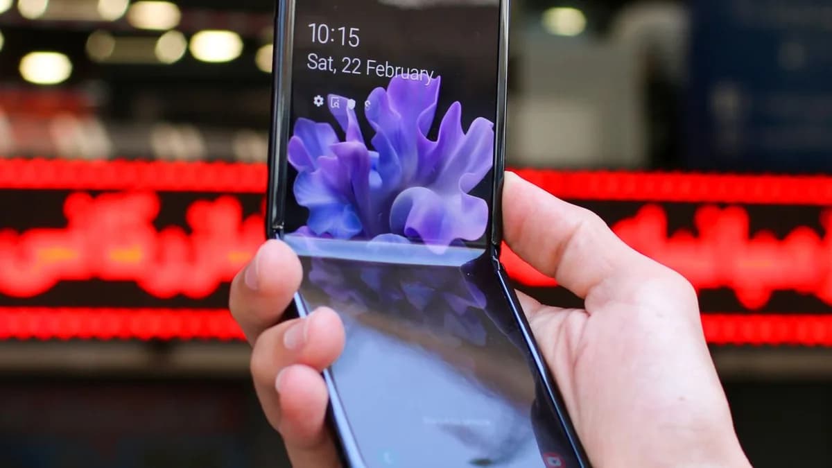 Close-up of a modern flip smartphone held in hand, showcasing innovative technology outdoors in a bustling city.