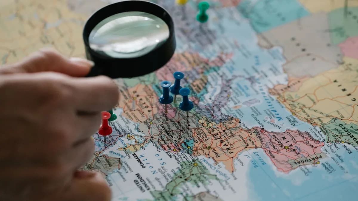 Magnifying glass focuses on pins highlighting travel destinations on a world map.