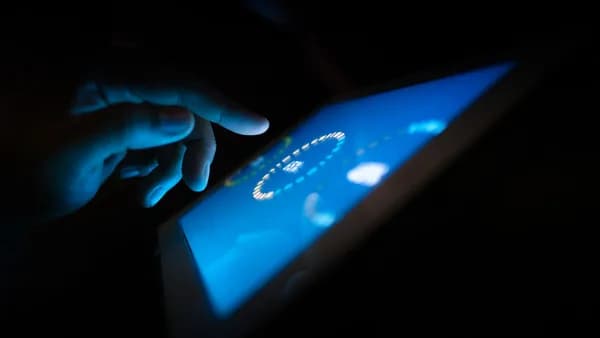 Close-up of a hand interacting with a glowing touchscreen in a dark setting, highlighting technology use.