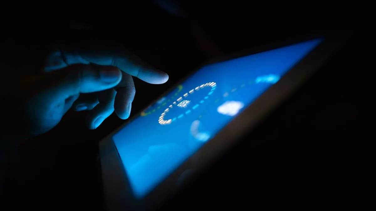 Close-up of a hand interacting with a glowing touchscreen in a dark setting, highlighting technology use.