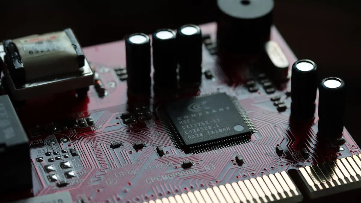 Detailed view of a red circuit board with various electronic components and microchip.