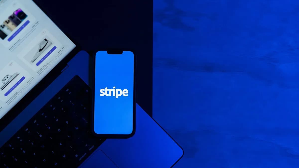 A smartphone displaying the Stripe app placed on a laptop keyboard with a blue monochromatic tone.