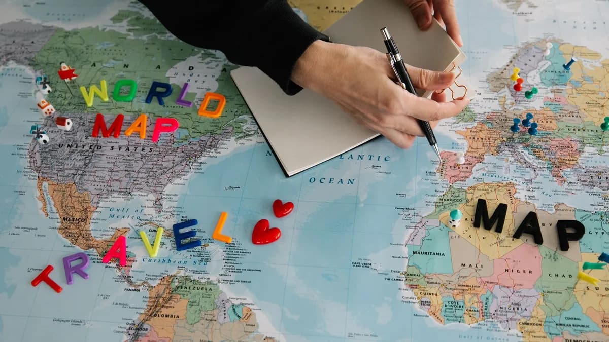 Hands holding pen and notebook over vibrant world map planning a journey.